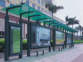 Municipal bus shelter with a green polycarbonate canopy roof.